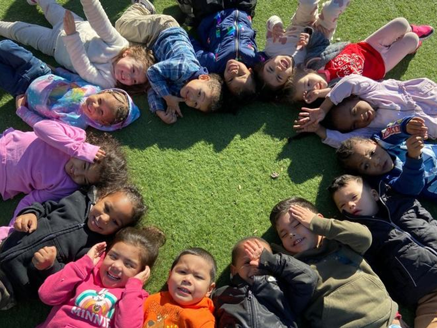Smiling teacher playing with two preschoolers at a sunlit table at Tots Unlimited daycare